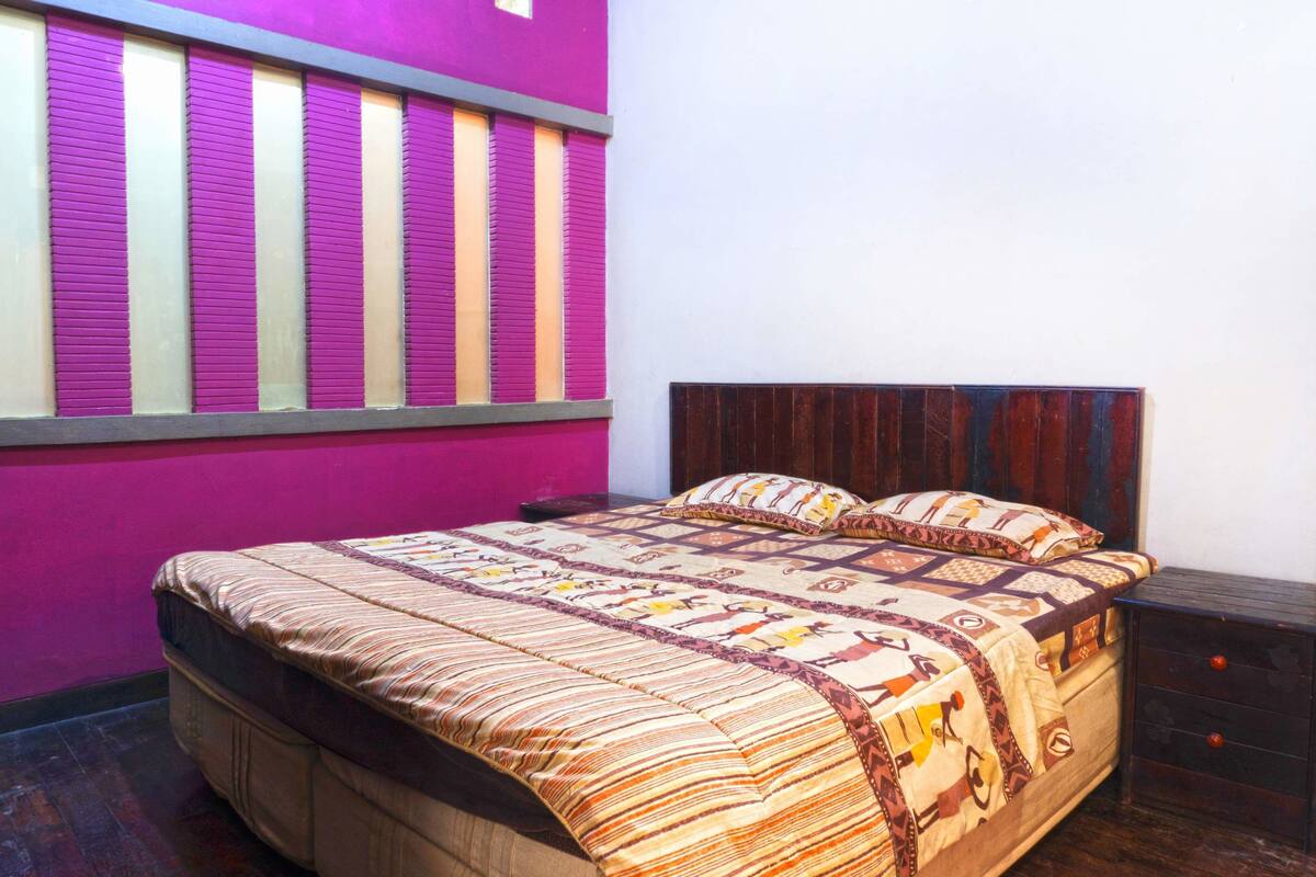 Un dormitorio con cama, cabecero de madera y una ventana con persianas.