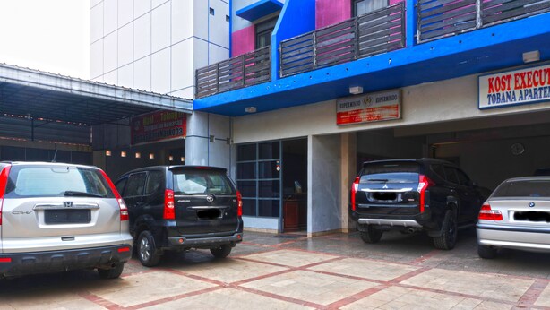 A parking area with multiple cars parked in front of a building with a blue and white facade.