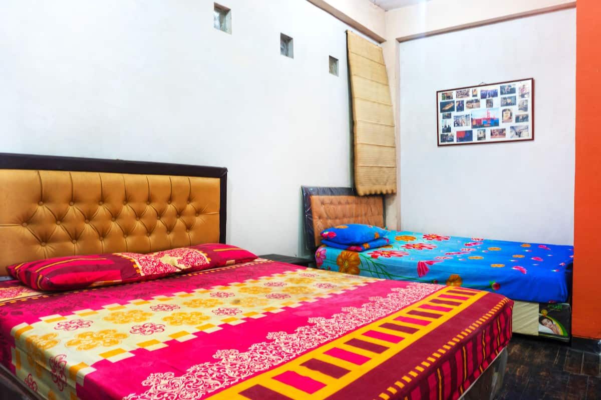 Una habitación con una cama grande, una cama más pequeña y una pared con un collage de fotos.