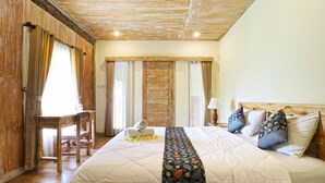 A hotel room with a large bed, wooden headboard, a desk, and a chair.