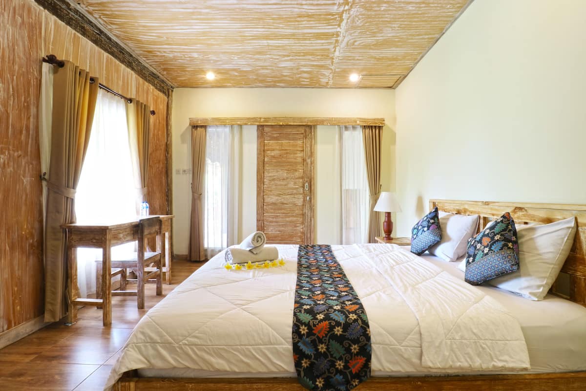 Een hotelkamer met een groot bed, een houten hoofdeinde, een bureau en een stoel.
