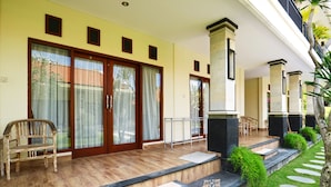 A hotel entrance with a wooden porch, a chair, and a staircase leading to the entrance.