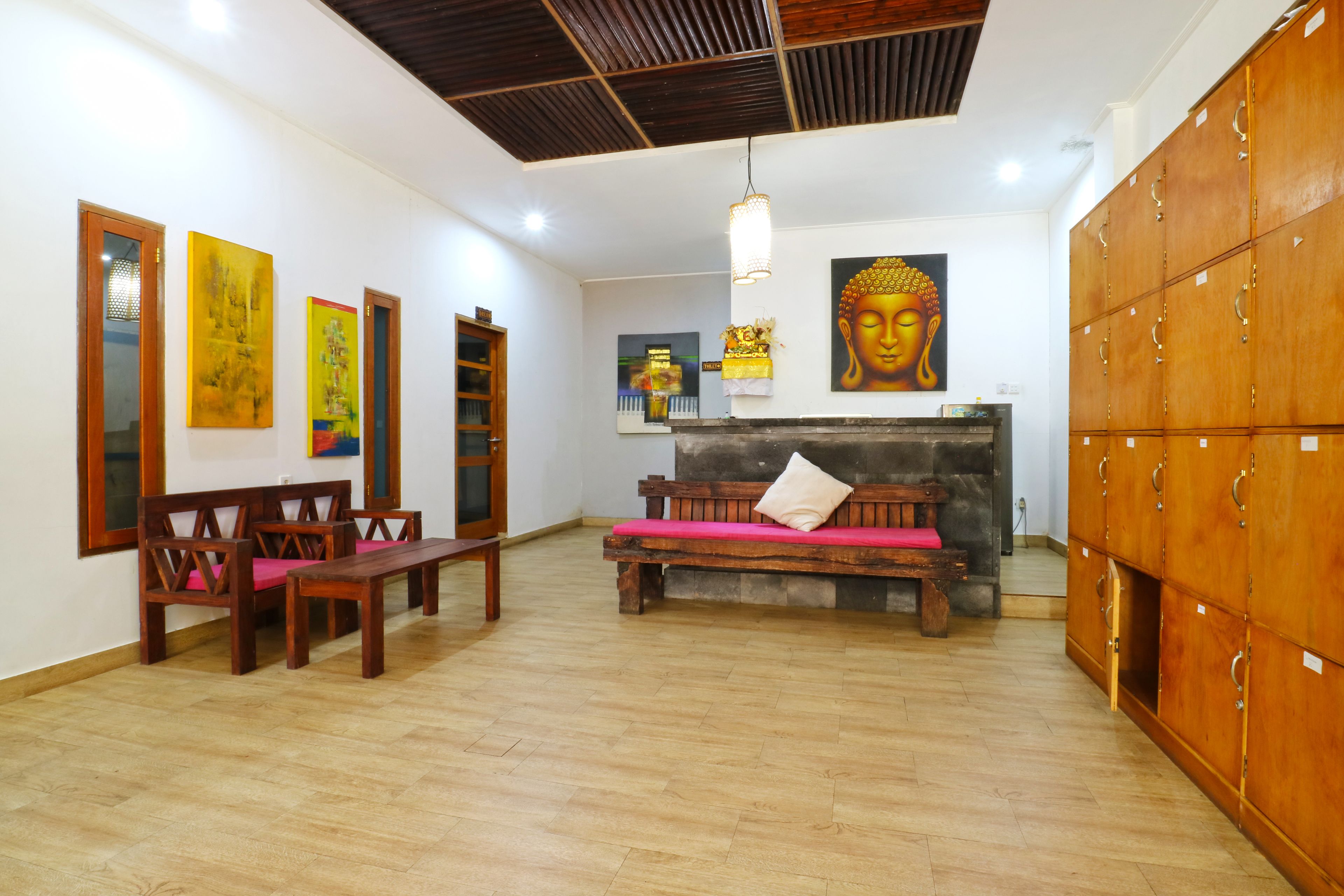 A spacious room with wooden furniture, a Buddha painting, and a wooden cabinet.