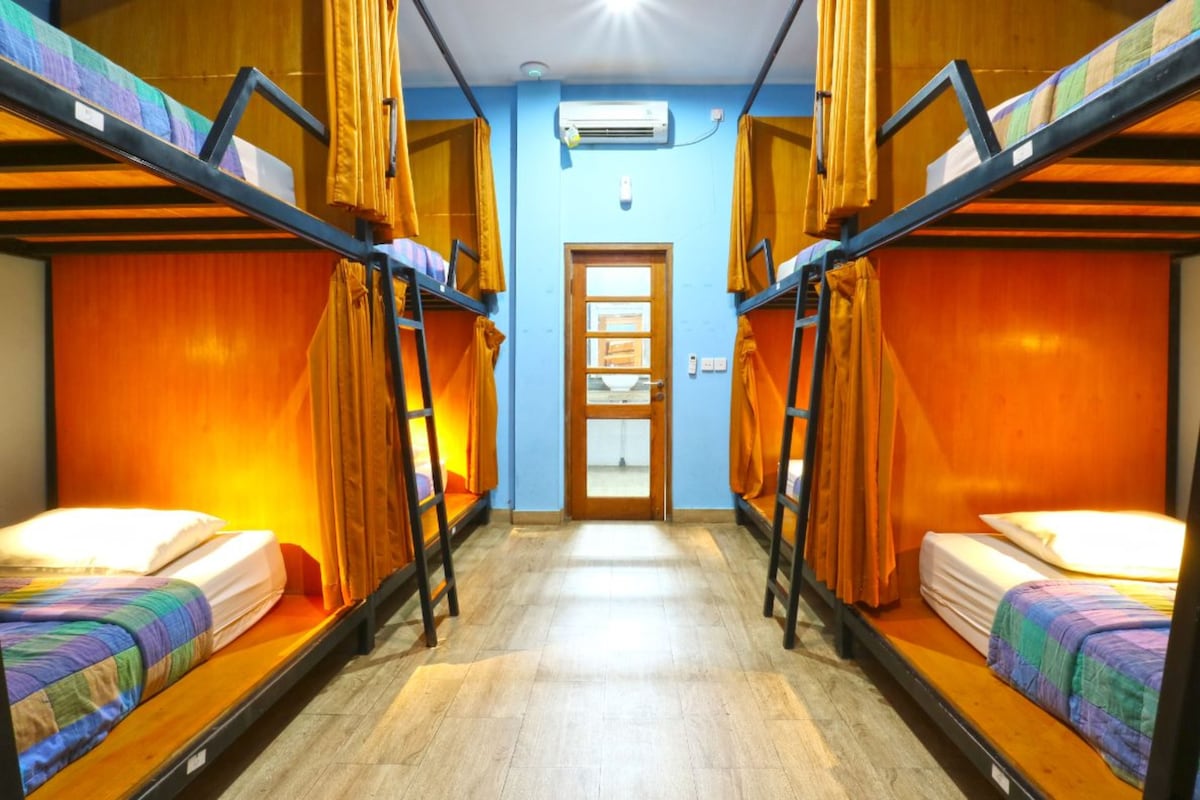 A room with bunk beds, a wooden floor, and a door with a window.
