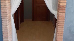A corridor with a wooden floor, brick walls, and a wooden door at the end. - B&B Villa Filomena (Serino)