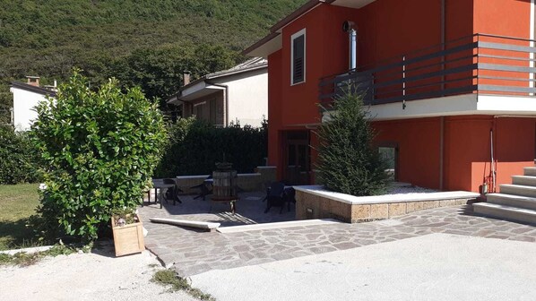 A red building with a stone patio, outdoor seating, and a small tree.