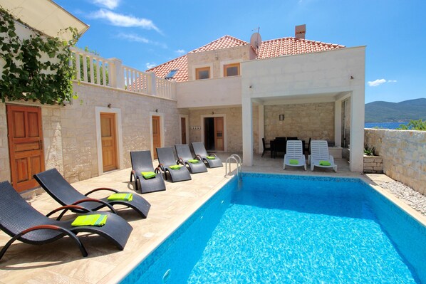 Relax by the serene pool surrounded by lounge chairs and a scenic landscape.