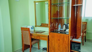 Une pièce comprenant un bureau en bois, une chaise, un miroir et un meuble avec des portes en verre.
