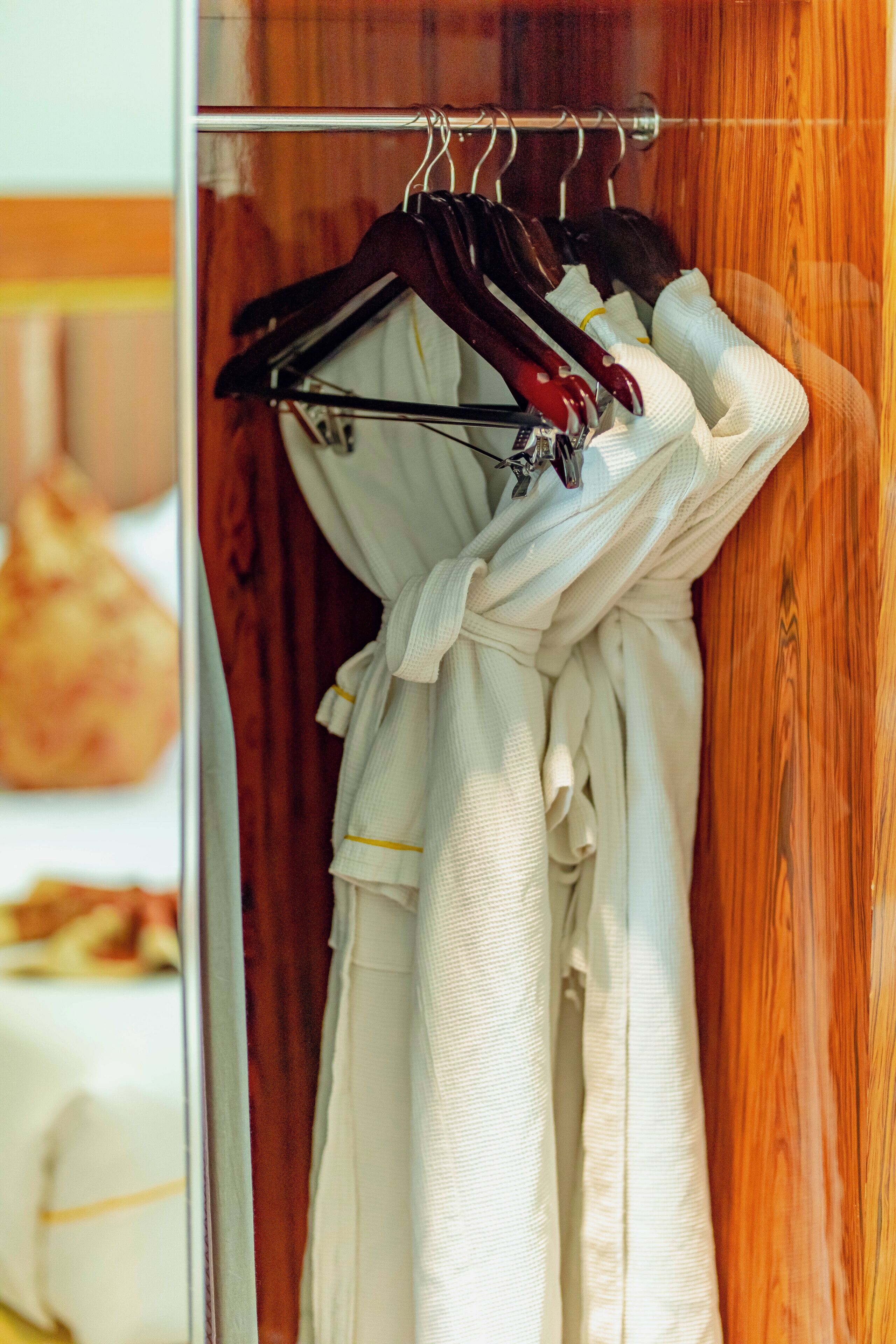 A white bathrobe hanging on a metal rack in a wooden room.