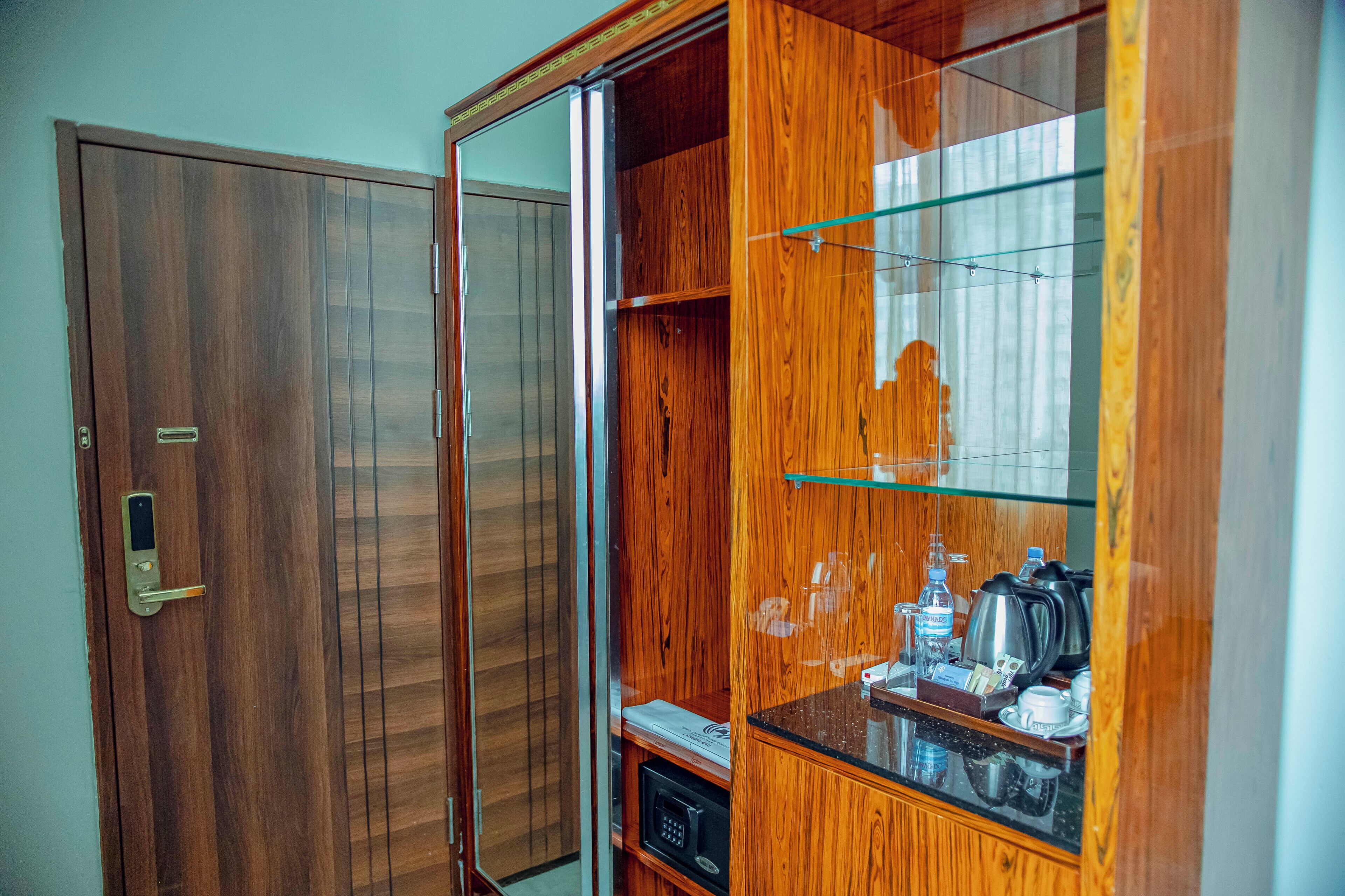 Un armario de madera con puerta de cristal, un microondas y una cafetera sobre la encimera.