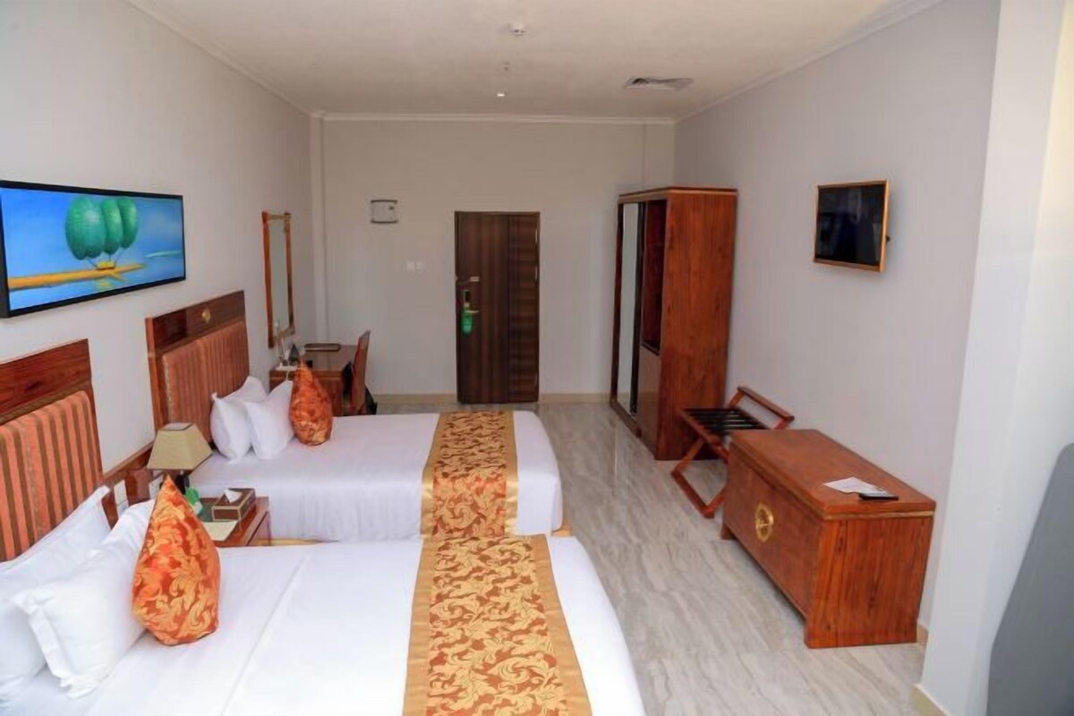 Ein Hotelzimmer mit zwei Betten, einem Schreibtisch, einem Kleiderschrank und einem Spiegel.