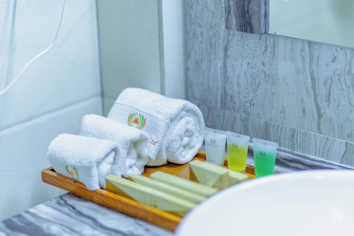 Une salle de bain avec un plateau en bois sur lequel sont posés des serviettes enroulées, un miroir et des articles de toilette.
