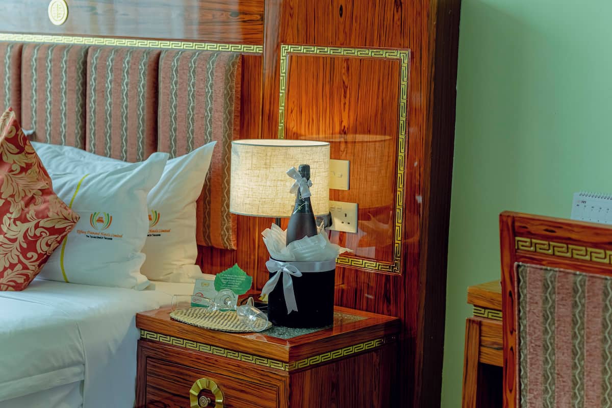 Une chambre d’hôtel avec un lit, une table de chevet dotée d’une lampe et un objet décoratif posé sur la table de chevet.