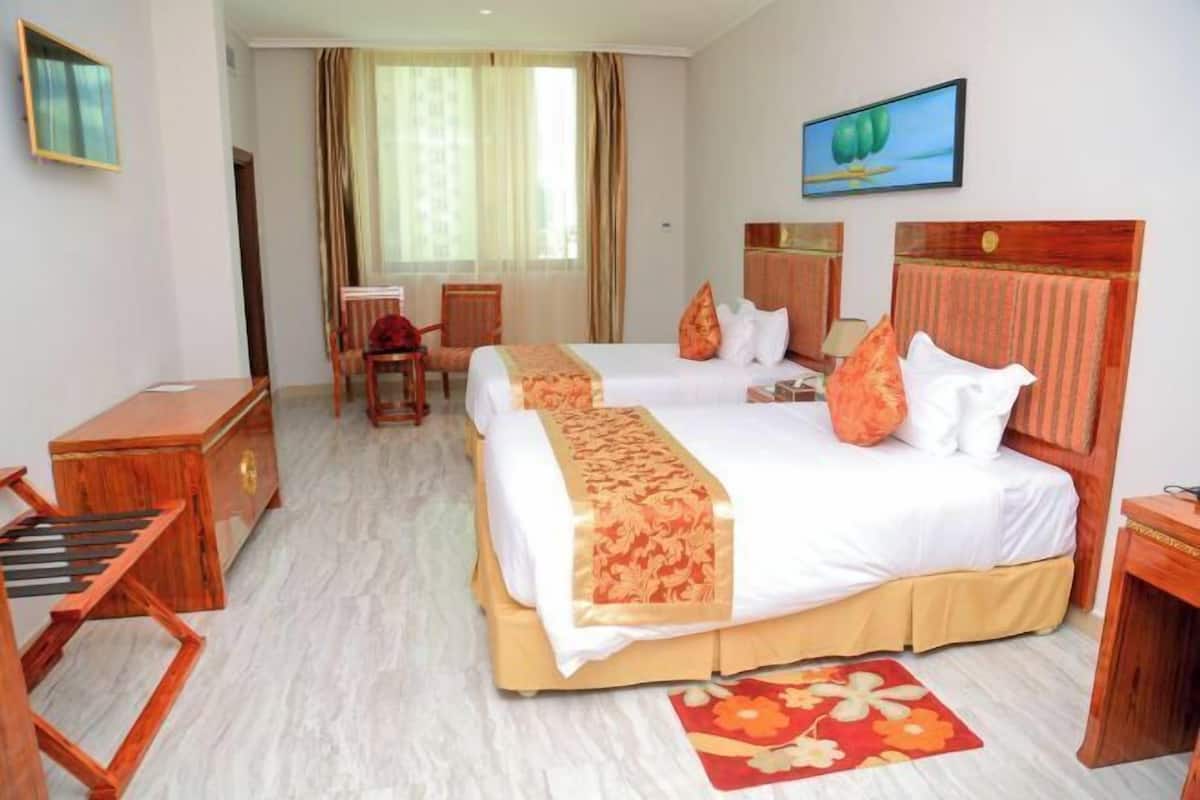 Une chambre d’hôtel avec un grand lit, un bureau, une chaise et une fenêtre avec des rideaux.