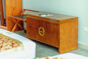 A wooden desk with a drawer, a chair, and a bed with a patterned bedspread.