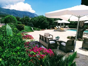 A patio area with outdoor seating, a pool, and a mountainous backdrop. - Summer Wine Friendly Resort (Corfu)