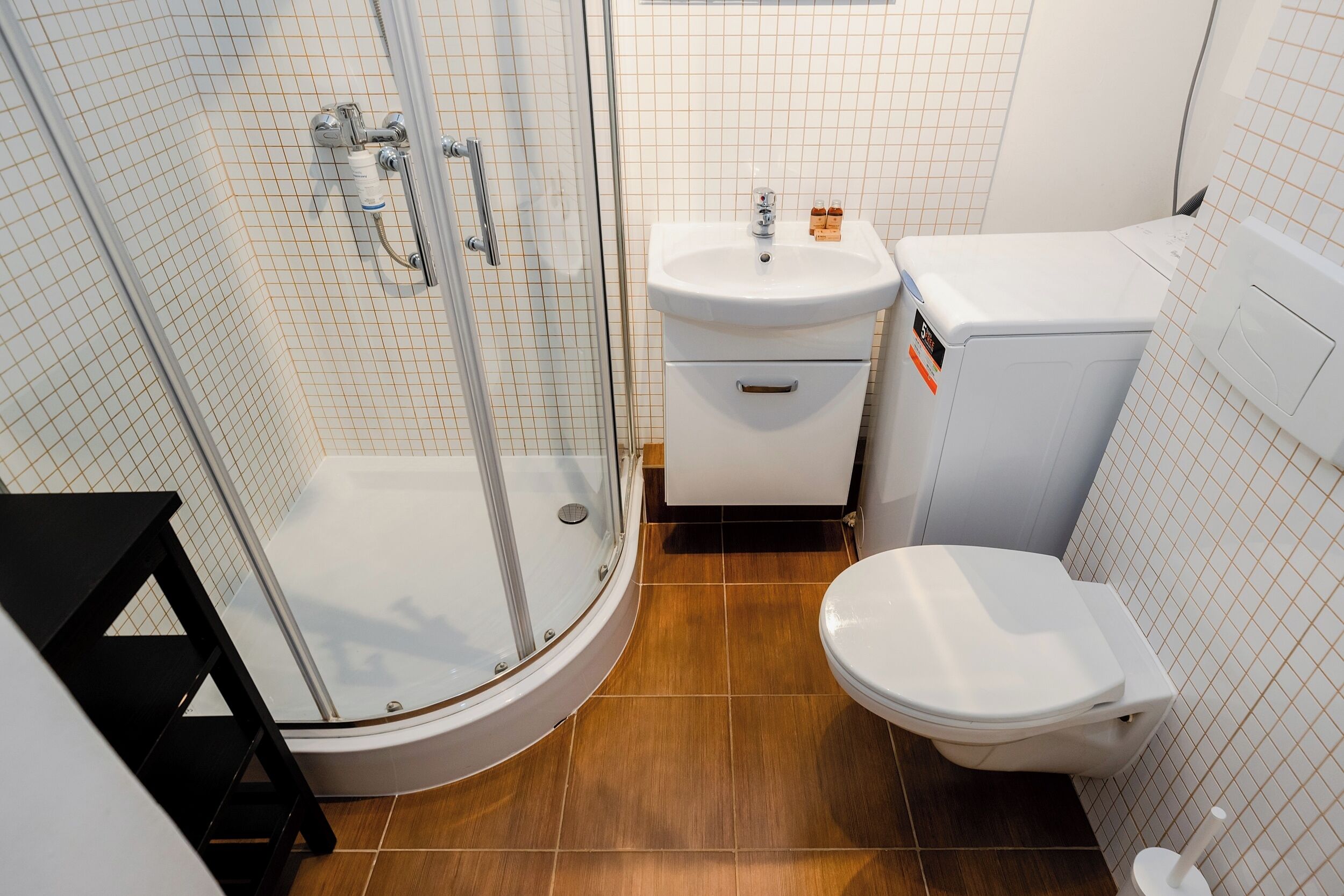 Un baño con ducha de mampara de vidrio, un lavabo blanco y un inodoro.