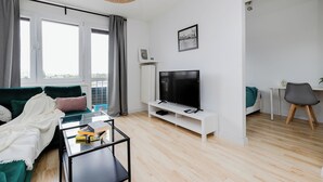 Una sala de estar moderna con un sofá, televisor y una pequeña mesa.