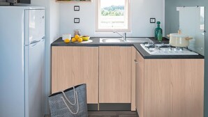 Cocina compacta con armarios de madera, un lavamanos integrado y un ventanal que proporciona luz natural.