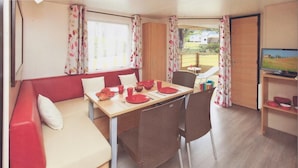 Interior compacto de una autocaravana con comedor, sofá y televisor.