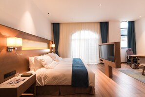 A hotel room with a bed, bedside lamps, a flat-screen TV, a desk with a chair, and a window with curtains. - Novotel Suzhou Tai Lake Santeh Hotel (Suzhou)