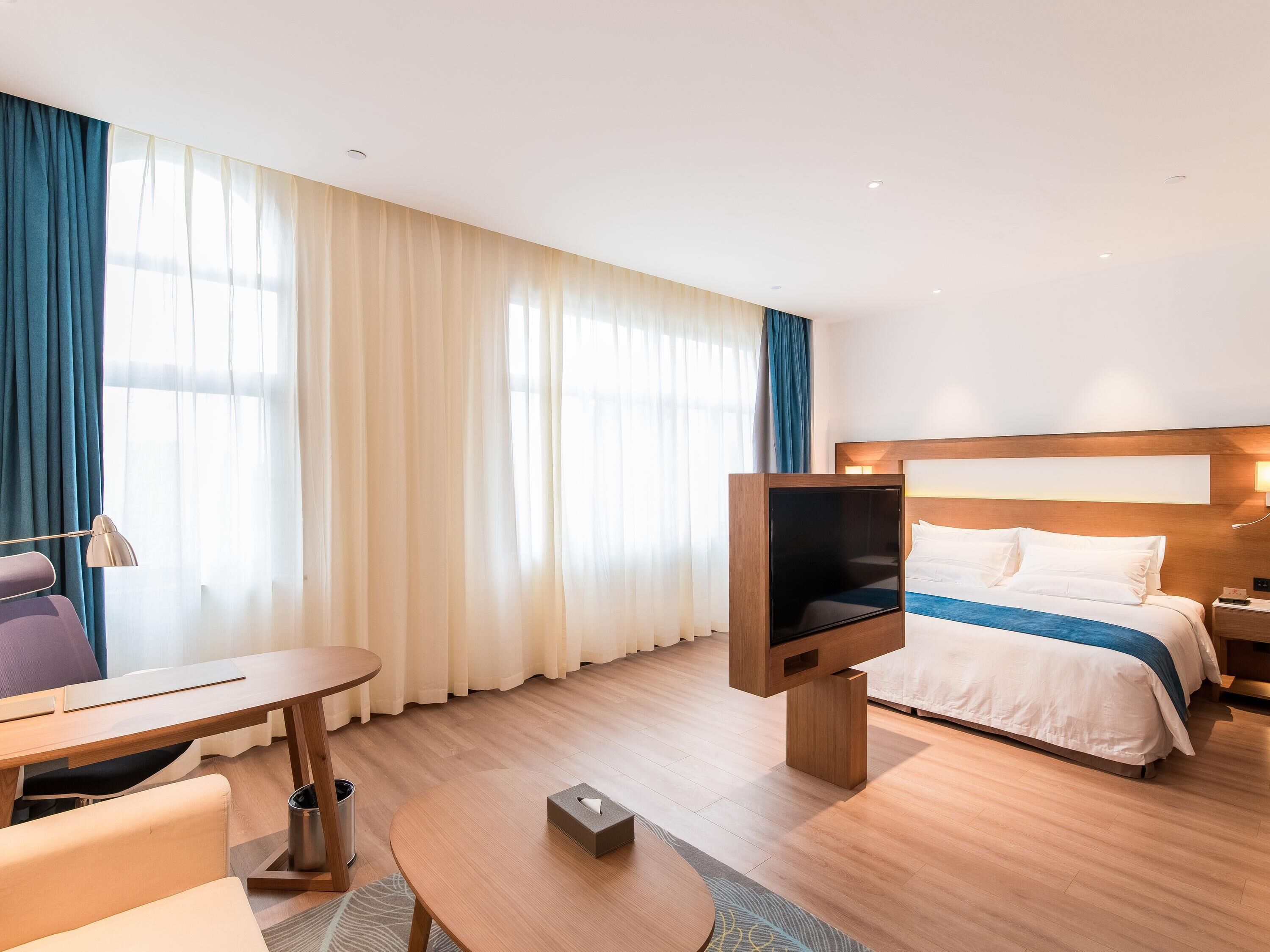 Une chambre d’hôtel avec un lit, un bureau, une chaise, une télévision et une lampe.