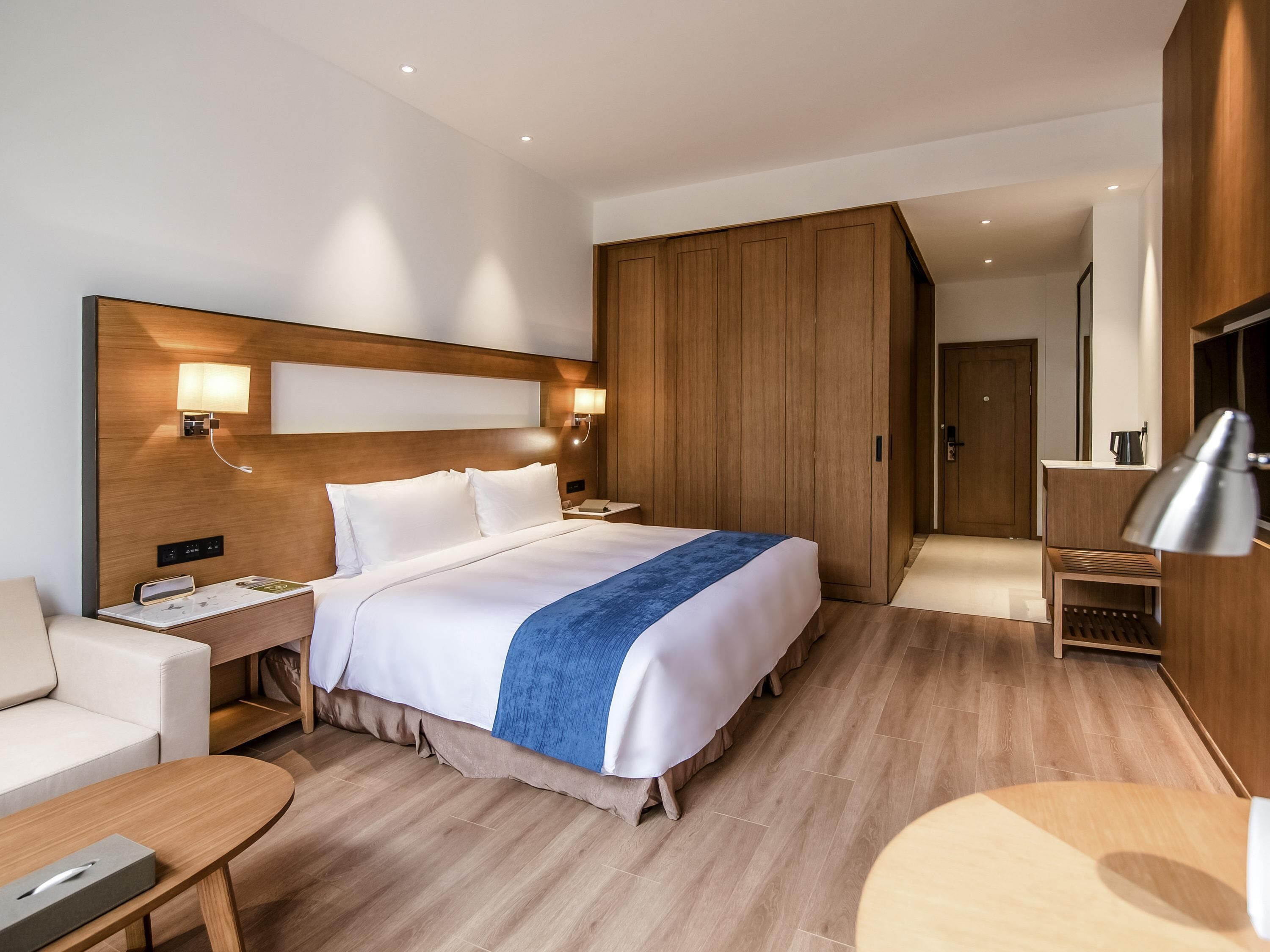 Une chambre d’hôtel avec un grand lit, des tables de chevet, un bureau, une armoire et un téléviseur.
