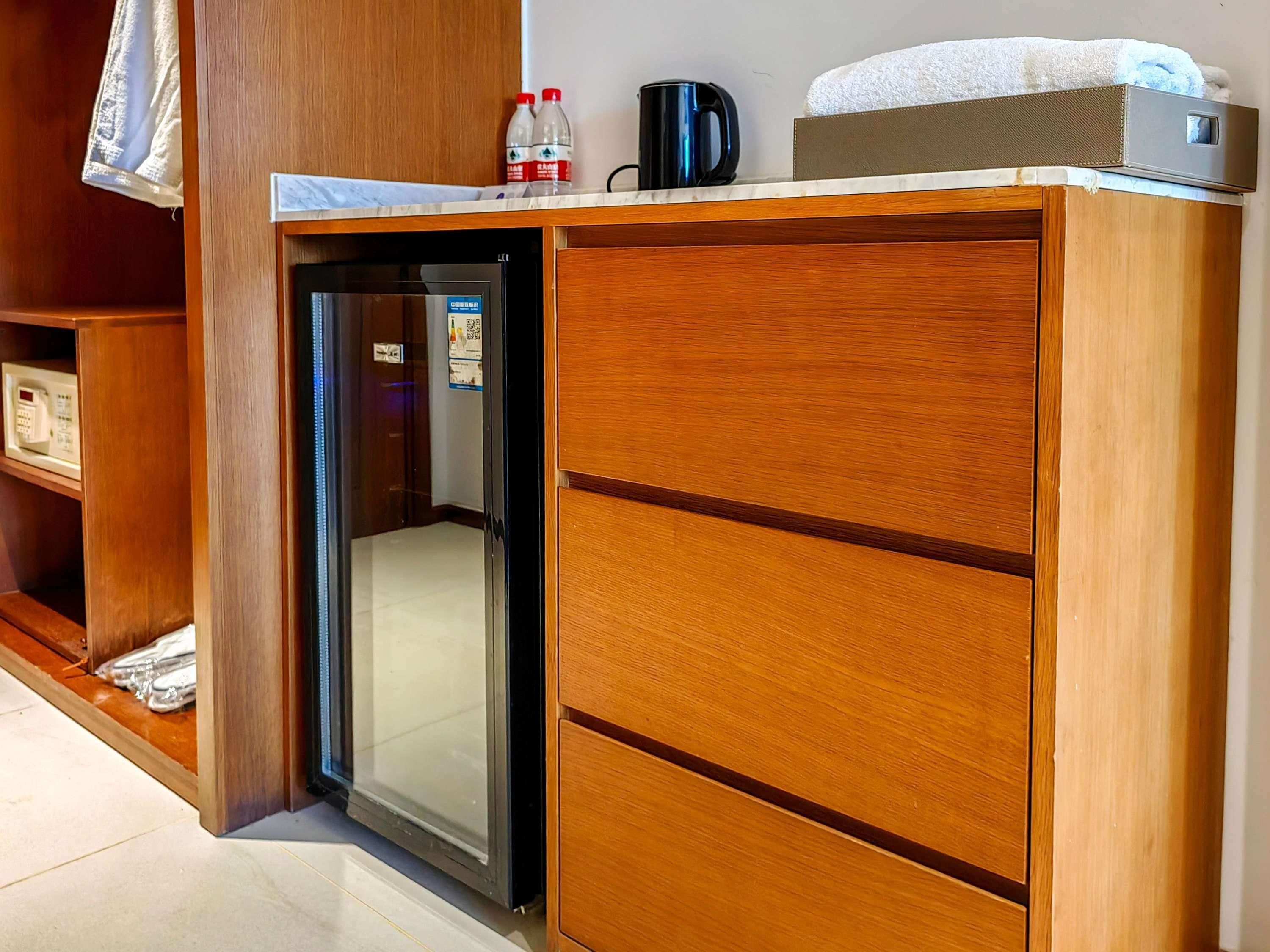 Ein Hotelzimmer mit einem Holzkorpus, einer Minibar und einem kleinen Kühlschrank.