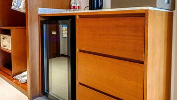 Ein Hotelzimmer mit einem Holzkorpus, einer Minibar und einem kleinen Kühlschrank.