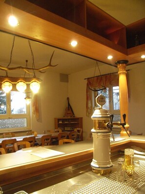 A cozy dining area with wooden tables and chairs, a beer tap, and a guitar on a shelf. - Landgasthof Marlishausen (Arnstadt)