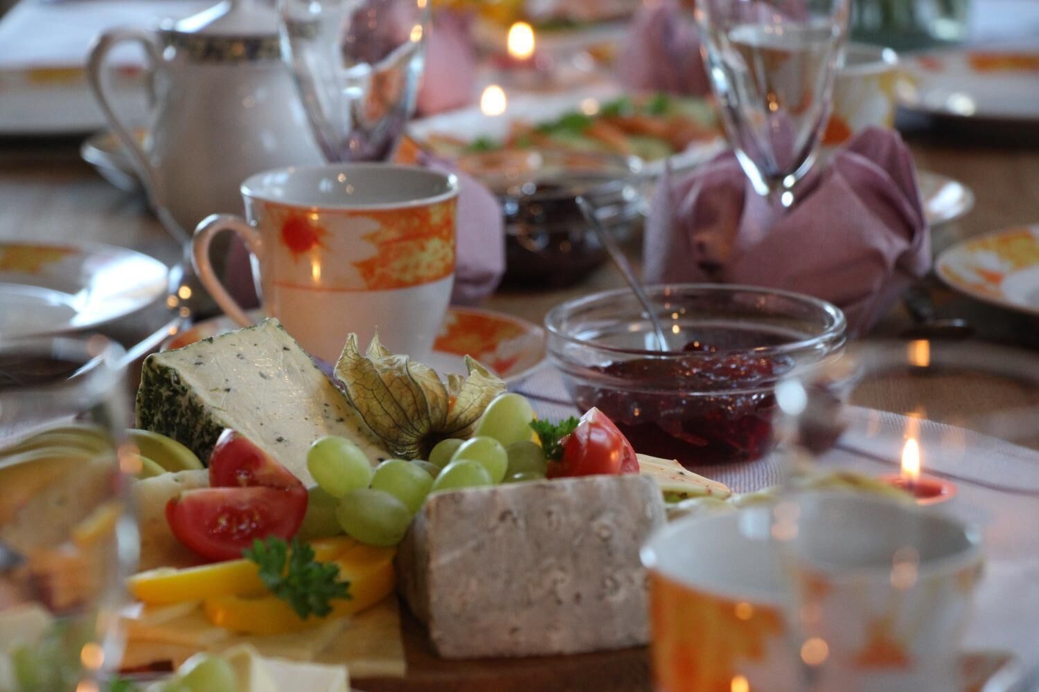 Una mesa servida con varios quesos, frutas y condimentos, evocando una escena de comida.