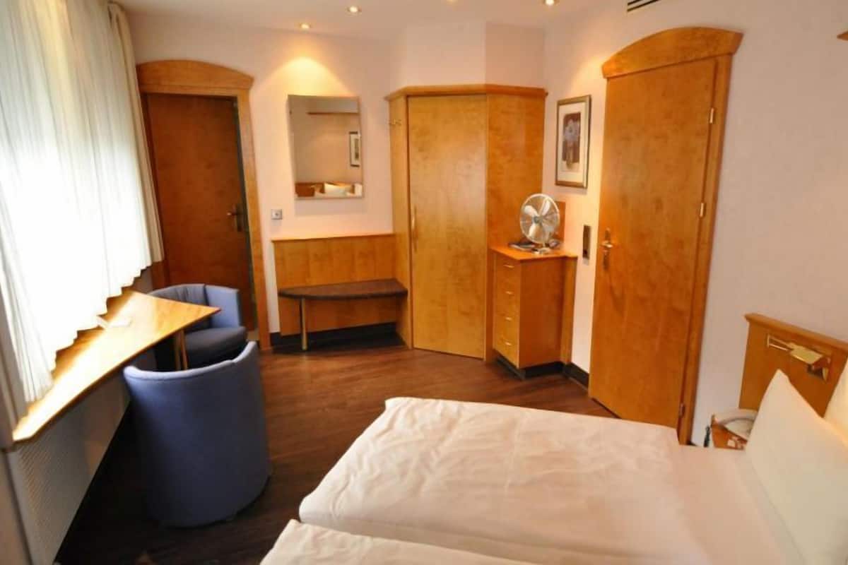 Ein Hotelzimmer mit einem Bett, einem Schreibtisch, einem Stuhl, einem Kleiderschrank und einem Spiegel.