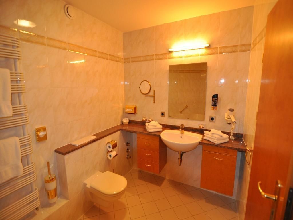 A bathroom with a toilet, sink, and mirror. There are towels and toiletries on the counter.
