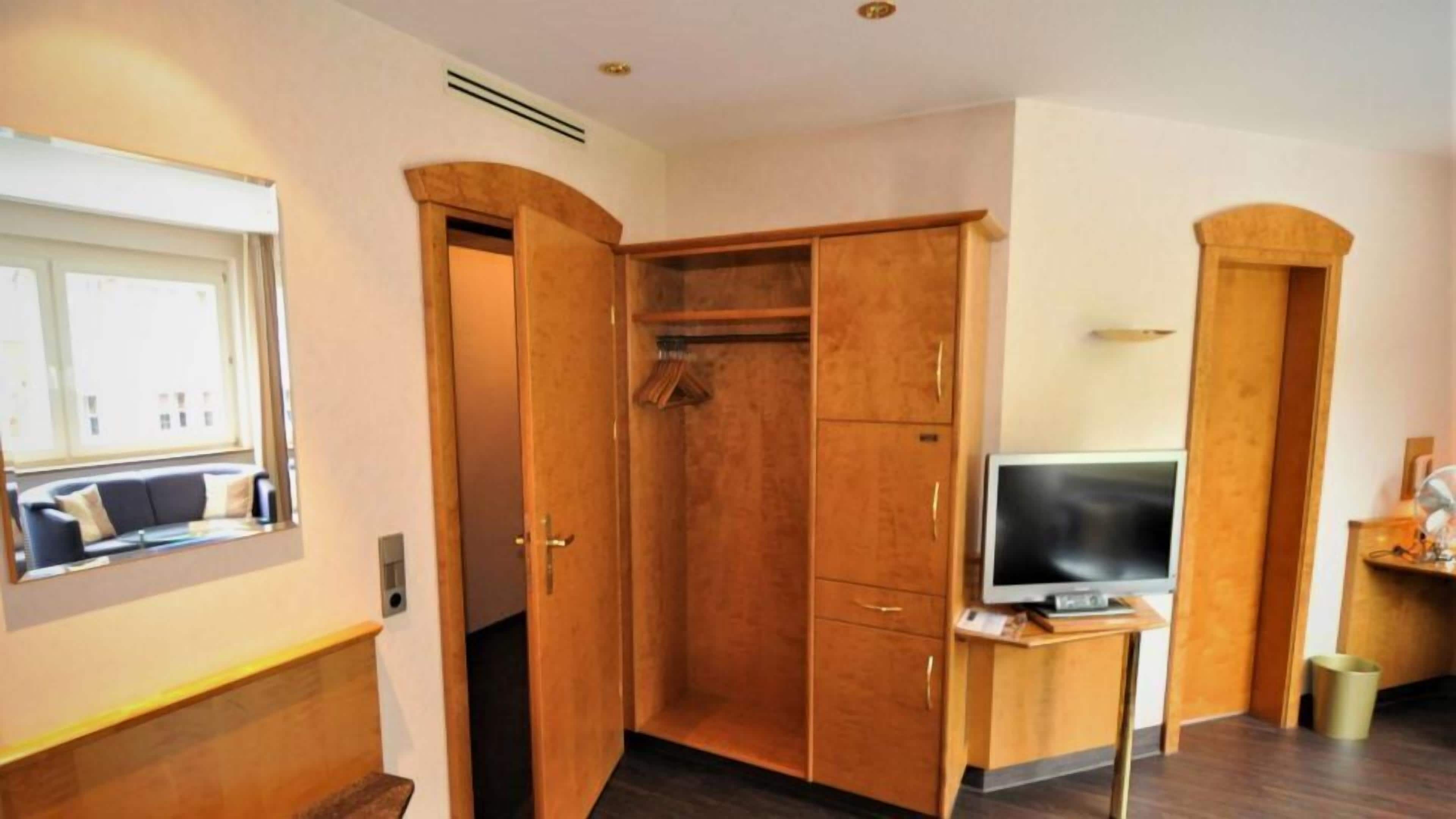 Ein Zimmer mit einem Holfischschrank, einem Fernseher auf einem Tisch und einem Fenster mit Blick.