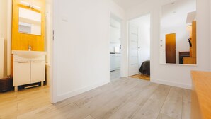 A modern hotel room with a wooden floor, a white sink, and a mirror above the sink. - ShortStayPoland Aleja Solidarności - B61 (Warsaw)