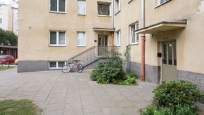 A multi-story building with a flat facade, a staircase leading to the entrance, and a bicycle parked outside. - ShortStayPoland Grottgera B198 (Warsaw)