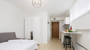 A modern hotel room with a bed, a small kitchen area, and a separate dining space. - ShortStayPoland Grottgera B198 (Warsaw)