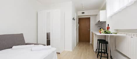A modern hotel room with a bed, a small kitchen area, and a separate dining space.