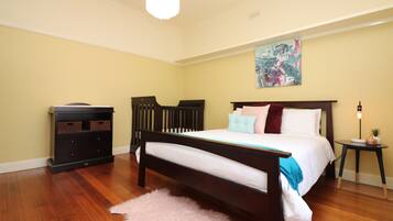 A bedroom with a wooden bed, a nightstand, a dresser, and a painting on the wall.
