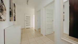 A hallway with white walls, a tiled floor, and a dark wooden door. - ShortStayPoland Krakowska - B65 (Warsaw)