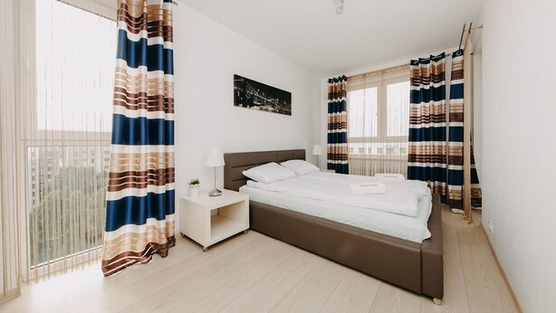 A bedroom with a bed, nightstand, and curtains. - ShortStayPoland Krakowska - B65 (Warsaw)