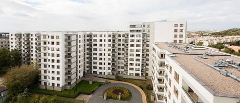 A high-rise residential building with multiple balconies, a rooftop garden, and a playground area.