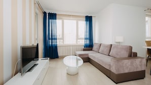 A modern living room with a sectional sofa, a glass coffee table, and a flat-screen TV on a white console. - ShortStayPoland Krakowska - B65 (Warsaw)