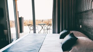 A hotel room with a large bed, a view of a fenced outdoor area, and a table with chairs outside. - Hôtel de la Baie de Wissant (Wissant)