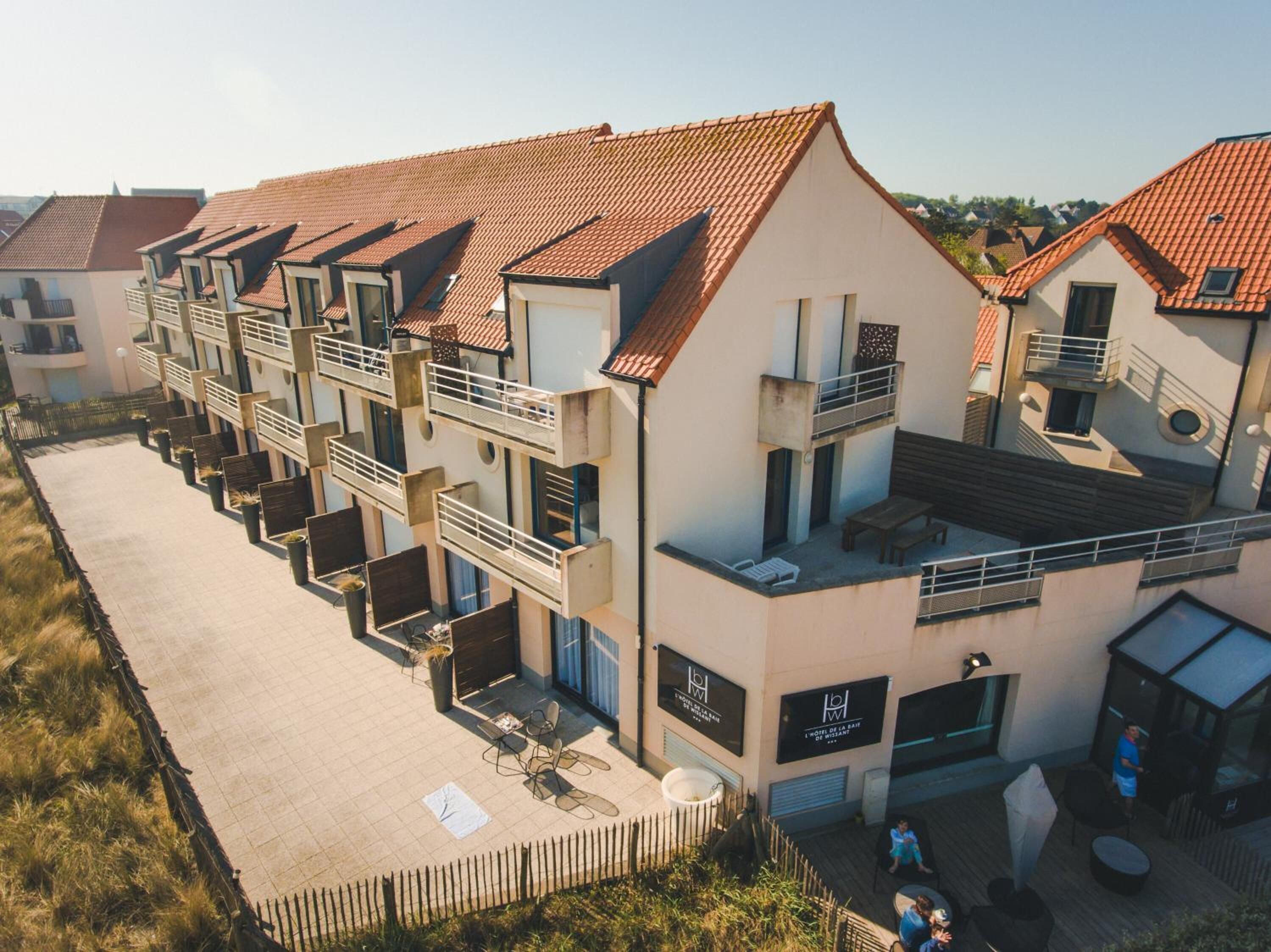 A row of modern, multi-story buildings with balconies and outdoor seating areas.