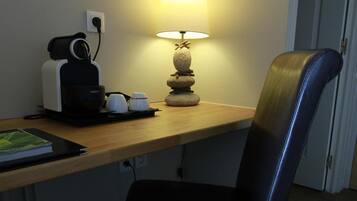 Ein kleiner Schreibtisch mit Lampe, Stuhl und Kaffeemaschine.