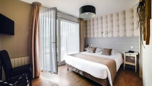 A modern hotel room with a large bed, a desk, a chair, and a TV mounted on the wall. - Hôtel de la Baie de Wissant (Wissant)