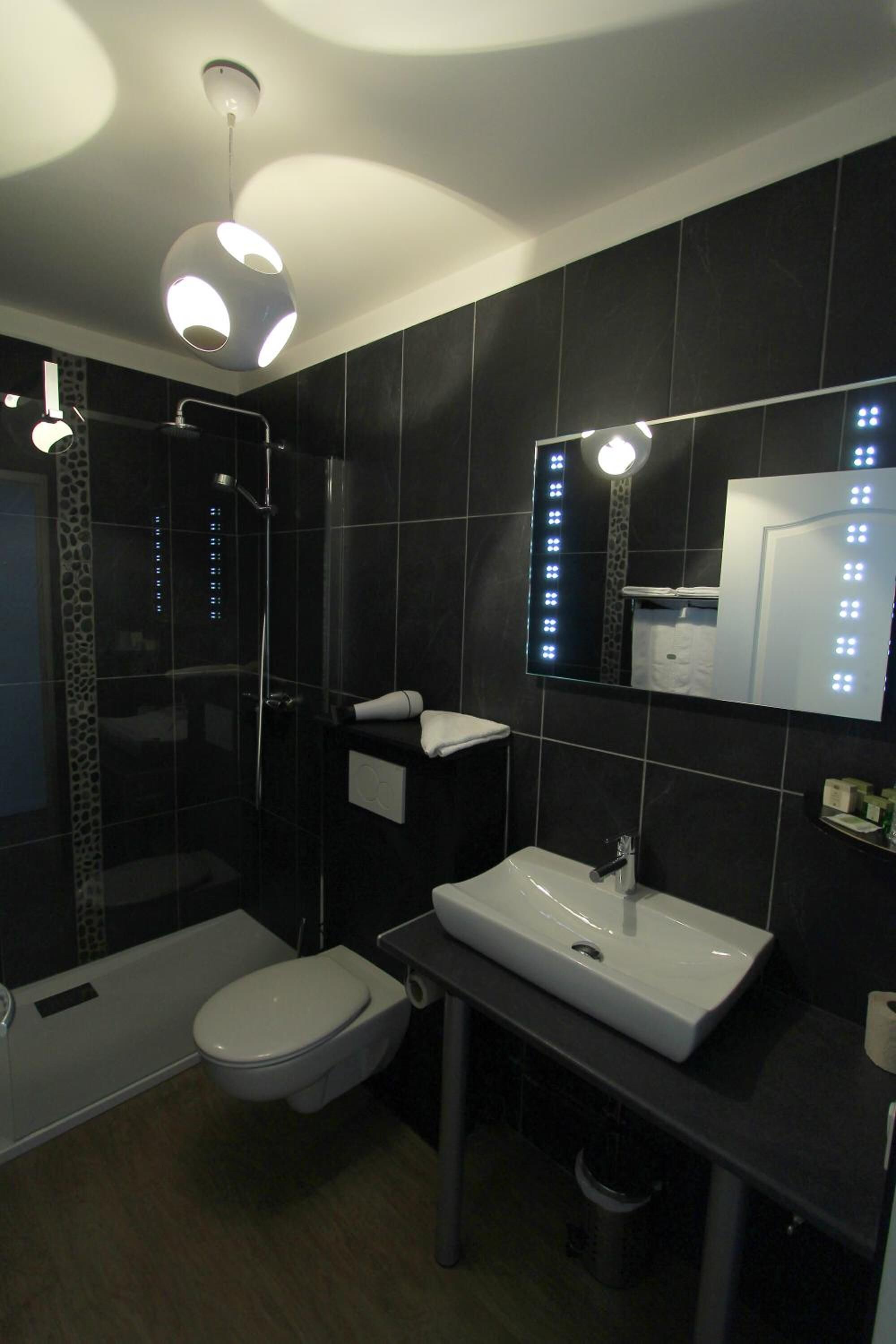 A modern bathroom with a glass-enclosed shower, a white toilet, and a sink with a mirror above it.