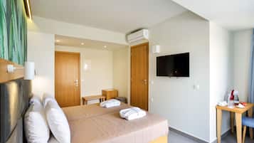 Quarto de hotel com uma cama, televisão, escrivaninha e uma cadeira.