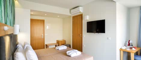 A hotel room with a bed, a TV, a desk, and a chair.